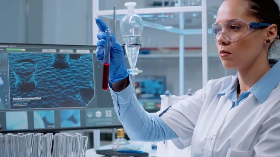 medicine scientist using computer while holding test tube